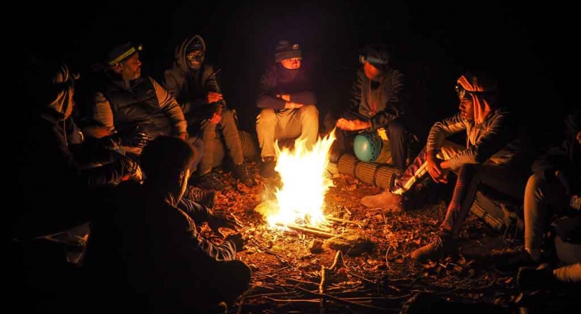a group of students sit around a campfire on an outward bound course in the blue ridge mountains